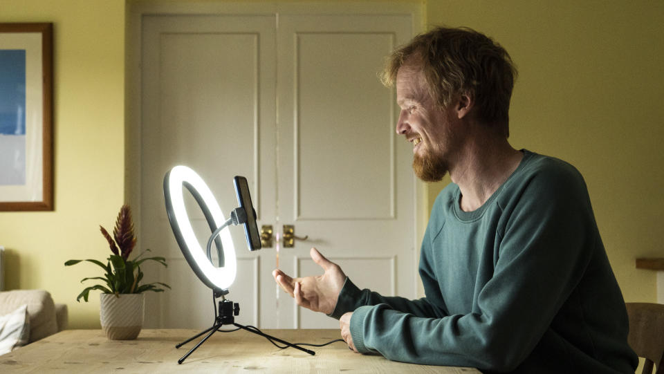 right light for phone on wooden table, powered up and illuminating person talking to camera