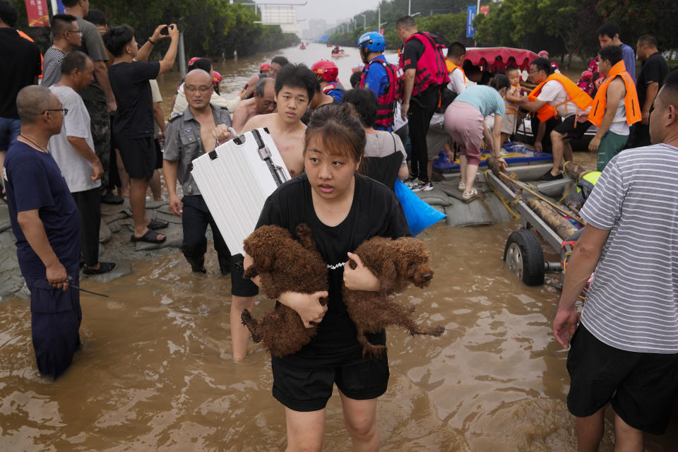 A woman carries her pet dogs as residents are evacuated on rubber boats through floodwaters in Zhuozhou in northern China's Hebei province, south of Beijing, Wednesday, Aug. 2, 2023. China's capital has recorded its heaviest rainfall in at least 140 years over the past few days. Among the hardest hit areas is Zhuozhou, a small city that borders Beijing's southwest. (AP Photo/Andy Wong)