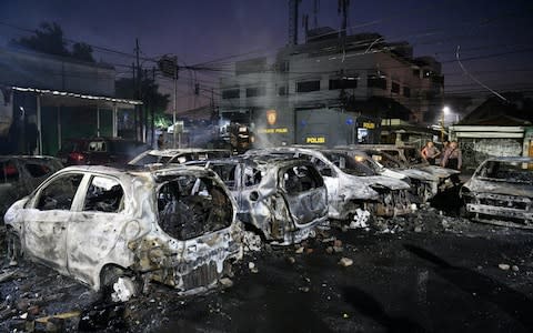 Police officers inspect the damage after cars were set on fire in Jakarta  - Credit: Reuters