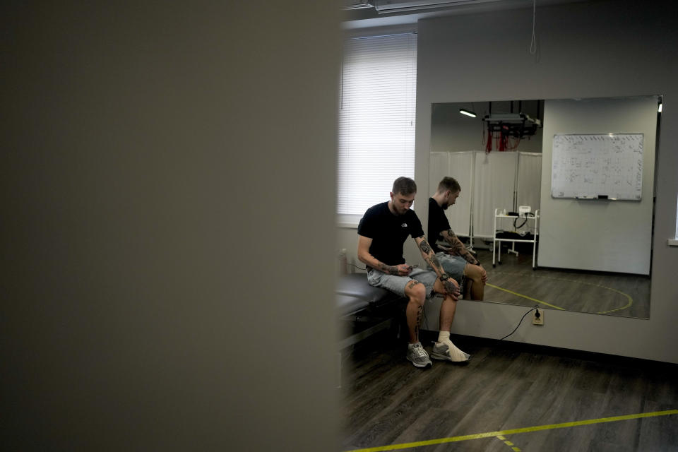 Vladislav Zahorodnii checks his phone at a clinic in Kyiv, Ukraine, Friday, June 17, 2022. Zahorodnii was evacuated from Azovstal by helicopter on March 31, after three failed earlier attempts. It was Zagorodniy's first helicopter flight. The Mi-8 took fire on its way out, killing one of its engines. The other one kept them airborne for the remainder of the 80-minute early morning dash to Dnipro city on the Dnieper River in central Ukraine. (AP Photo/Natacha Pisarenko)