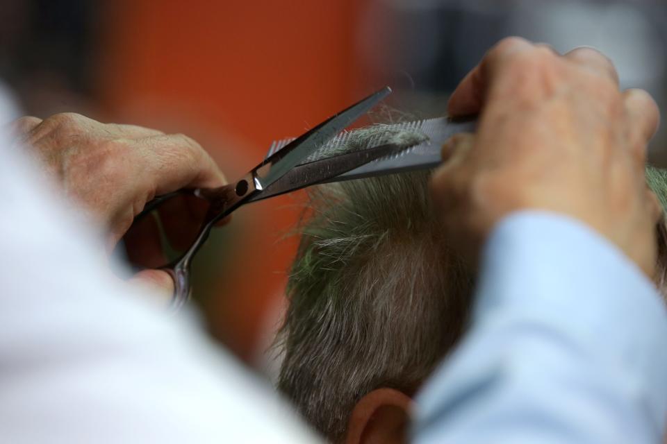 Tom Bergman trims the ends of Bruce Temple's hair Wednesday, Dec. 13, 2023 in Iowa City, Iowa.