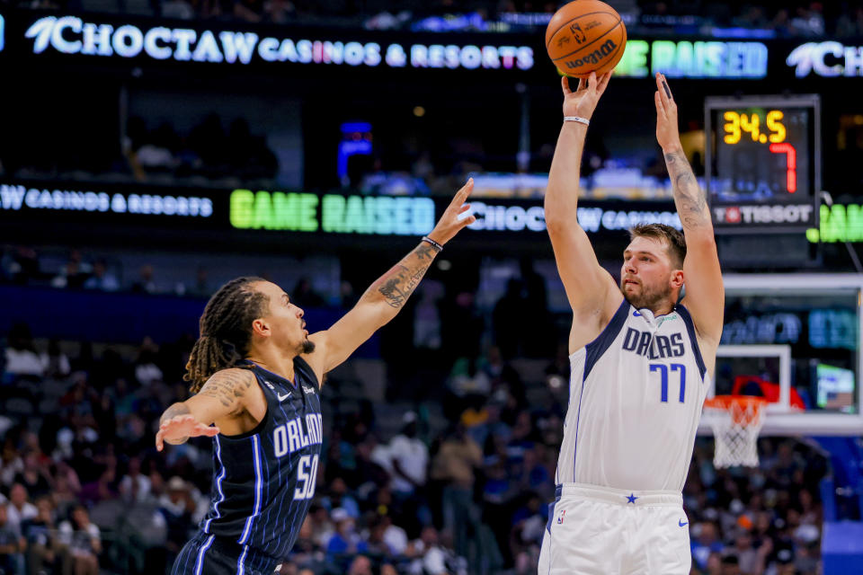 Dallas Mavericks point guard Luka Doncic (77) shoots over Orlando Magic point guard Cole Anthony, left, during the first half of a preseason NBA basketball game Friday, Oct. 7, 2022, in Dallas. (AP Photo/Gareth Patterson)