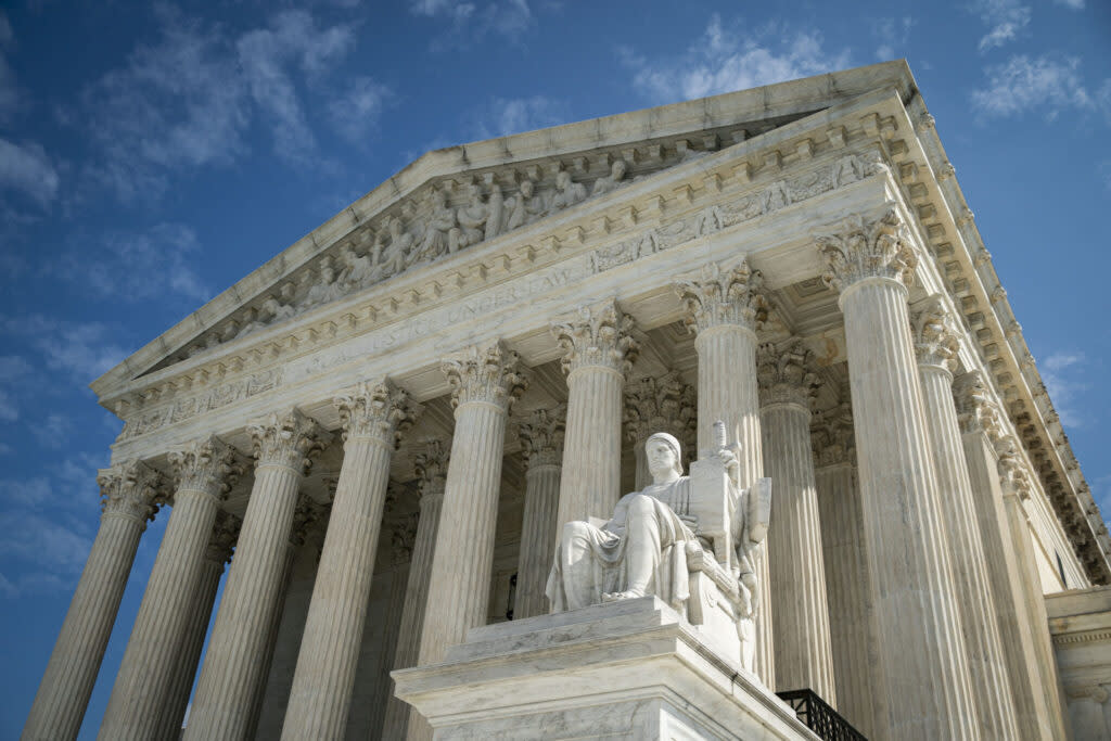 The U.S. Supreme Court building, with a statue of a seated classical figure in front of it.