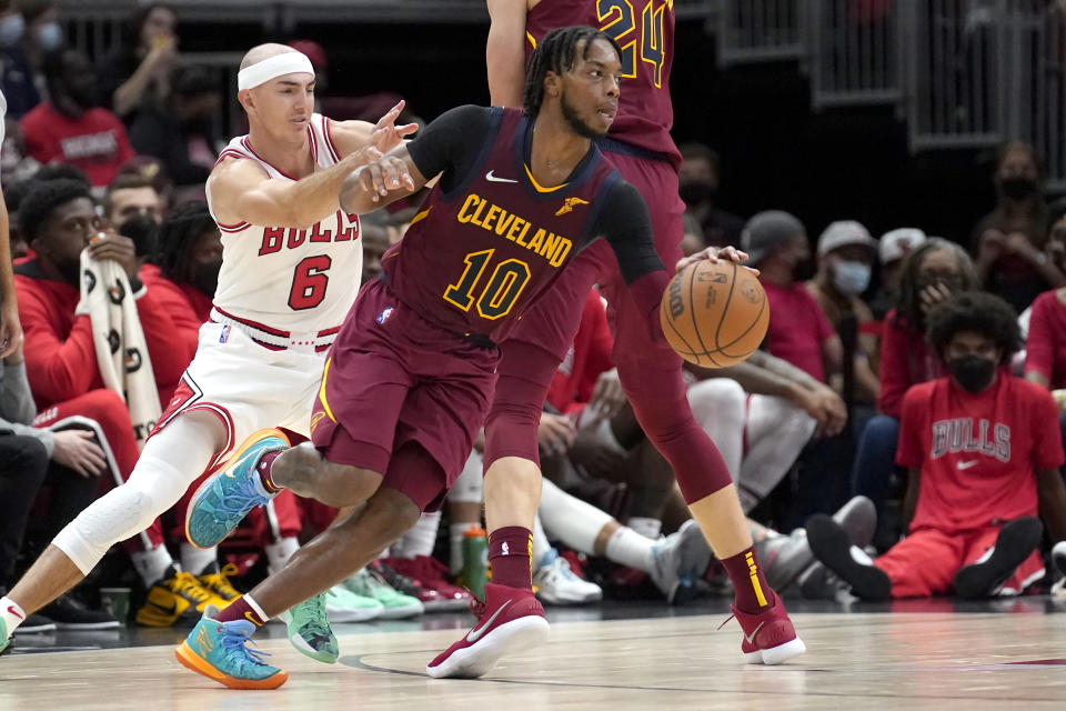 Cleveland Cavaliers' Darius Garland (10) drives around a pick set by Lauri Markkanen as Chicago Bulls' Alex Caruso (6) defends during the second half of an NBA preseason basketball game Tuesday, Oct. 5, 2021, in Chicago. The Bulls won 131-95. (AP Photo/Charles Rex Arbogast)