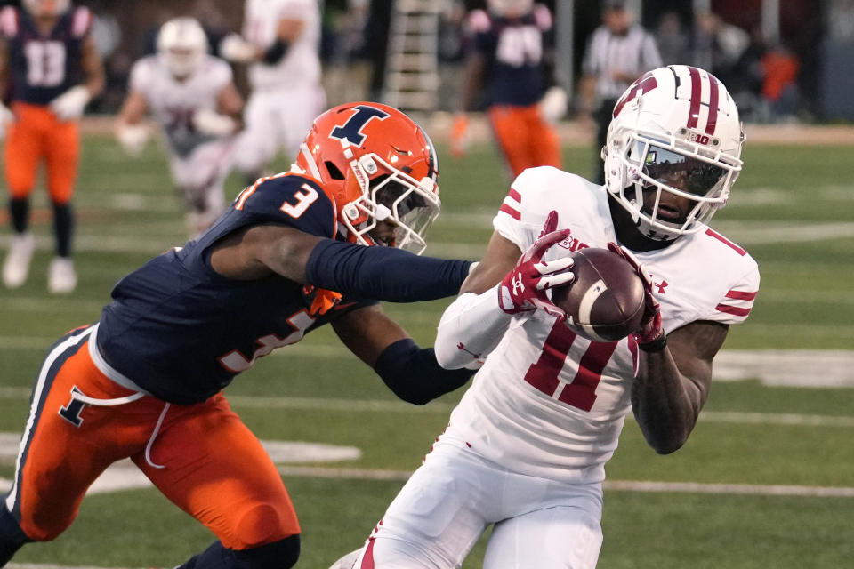 Wisconsin wide receiver Skyler Bell catches a deep pass from quarterback Braedyn Locke as Illinois defensive back Tahveon Nicholson defends during the second half of an NCAA college football game Saturday, Oct. 21, 2023, in Champaign, Ill. (AP Photo/Charles Rex Arbogast)