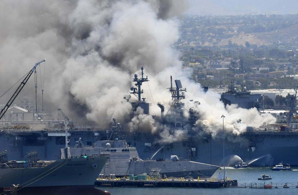 FILE - In this July 12, 2020, file photo, smoke rises from the USS Bonhomme Richard at Naval Base San Diego in San Diego, after an explosion and fire on board the ship at Naval Base San Diego. A sailor accused of starting the fire that destroyed the USS Bonhomme Richard will face a court martial for arson. The Navy notified Ryan Mays on Friday, Feb. 25, 2022, that he was to be tried in military court on two counts for the July 2020 blaze that injured dozens of personnel aboard. (AP Photo/Denis Poroy, File)