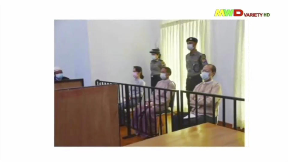 In this image from Myawaddy TV, a photograph shown during a news report showing the appearance of deposed Myanmar leader Aung San Suu Kyi, former President Win Myint, sitting 3rd from right, and former Naypyitaw Council chairman Dr. Myo Aung before a special court, shown while a report about Suu Kyi's case is read by a news presenter Monday, May 24, 2021, in Naypyitaw, Myanmar. Myanmar’s ousted leader Aung San Suu Kyi has made a court appearance in person for the first time since the military arrested her Feb. 1. (Myawaddy TV via AP)