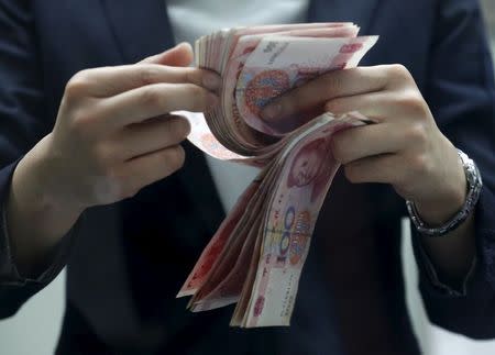 A clerk counts Chinese 100 yuan banknotes at a branch of a foreign bank in Beijing January 4, 2016. REUTERS/Kim Kyung-Hoon