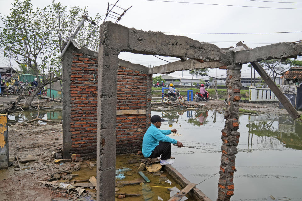 A man fishes in water inundating the area around an abandoned building due the rising sea levels and land subsidence in Sidogemah, Central Java, Indonesia, Monday, Nov. 8, 2021. World leaders are gathered in Scotland at a United Nations climate summit, known as COP26, to push nations to ratchet up their efforts to curb climate change. Experts say the amount of energy unleashed by planetary warming would melt much of the planet's ice, raise global sea levels and greatly increase the likelihood and extreme weather events. (AP Photo/Dita Alangkara)