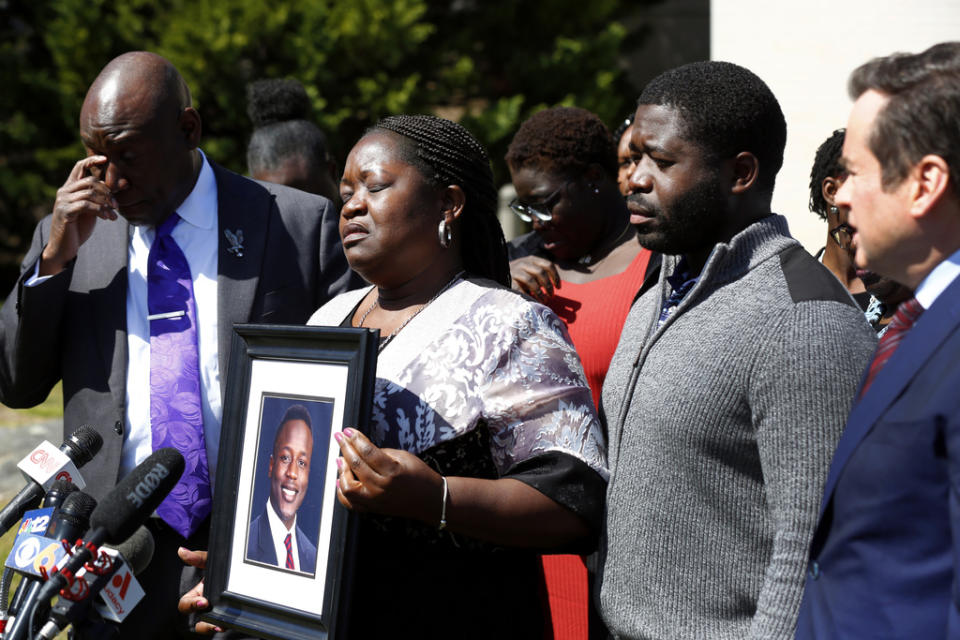 Caroline Ouko, mother of Irvo Otieno, holds a portrait of her son with attorney Ben Crump, left, her older son, Leon Ochieng and attorney Mark Krudys at the Dinwiddie Courthouse in Dinwiddie, Va., on Thursday, March 16, 2023. There is goodness in his music and that’s all I’m left with now — he’s gone,” Otieno’s mother, Caroline Ouko, said at the news conference while clutching a framed photo of her son. (Daniel Sangjib Min/Richmond Times-Dispatch via AP)