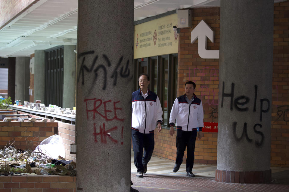 Hong Kong Polytechnic University Vice President Alexander Wai, left, walks through the campus after leading a search of the campus for remaining protestors in Hong Kong, Tuesday, Nov. 26, 2019. A weeklong police siege of a university in Hong Kong may be winding down, closing one of the more violent chapters in the city's long-running anti-government protests. (AP Photo/Ng Han Guan)