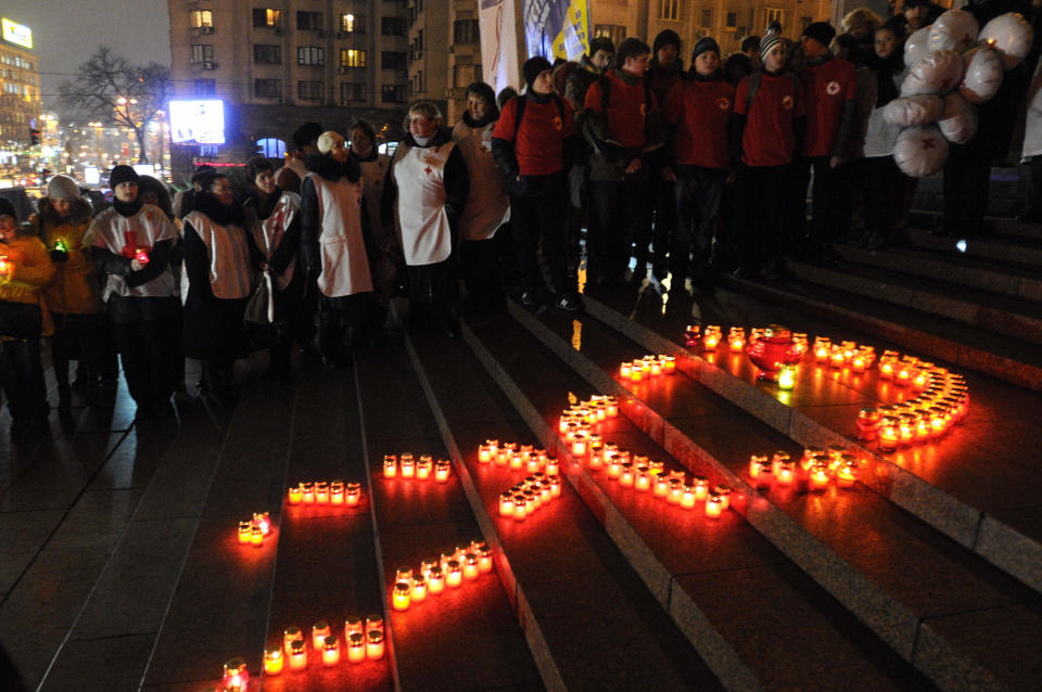 Ukrainian people make a red ribbon sign with candles ahead of the World AIDS Day, in Kiev, Ukraine, Thursday, Nov. 29, 2012. (AP Photo/Sergei Chuzavkov)