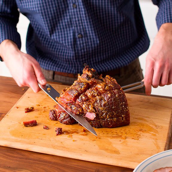 person cuts horizontally on half the ham to remove the bone