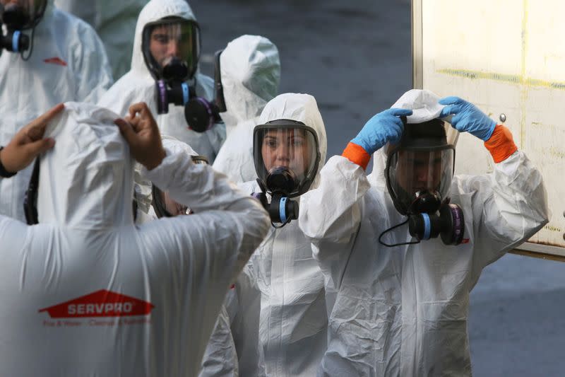 Members of a Servpro cleanup crew wear hazardous material suits as they prepare to enter Life Care Center of Kirkland, the Seattle-area nursing home at the epicenter of one of the biggest coronavirus outbreaks in the United States, in Kirkland