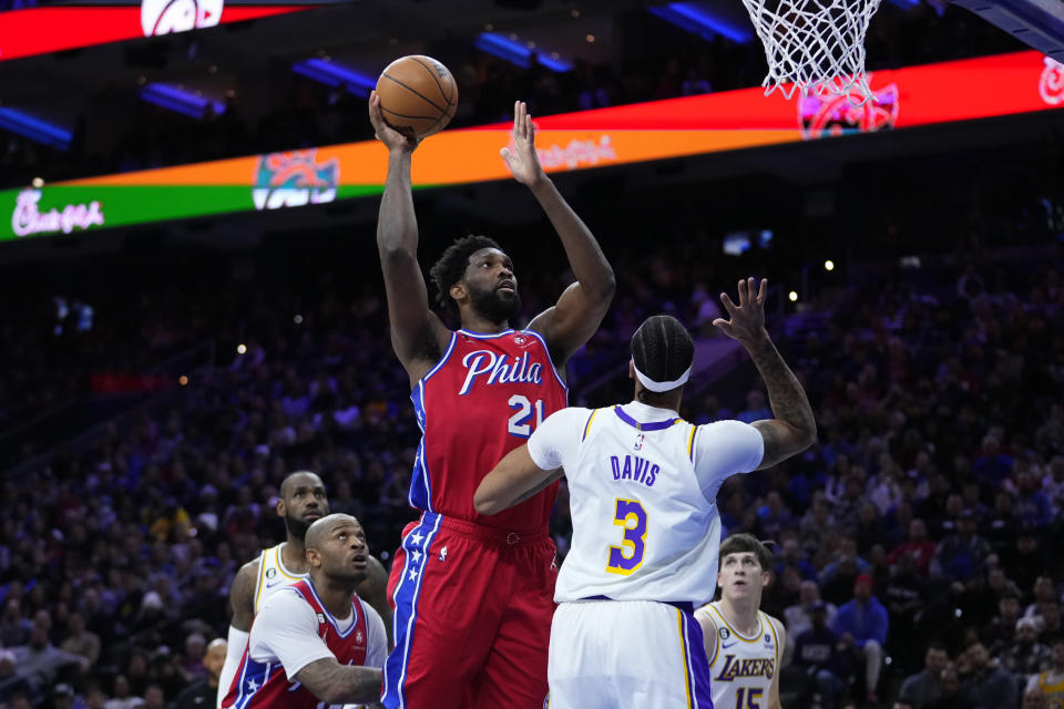 Philadelphia 76ers' Joel Embiid, center, goes up for a shot against Los Angeles Lakers' Anthony Davis during the first half of an NBA basketball game, Friday, Dec. 9, 2022, in Philadelphia. (AP Photo/Matt Slocum)