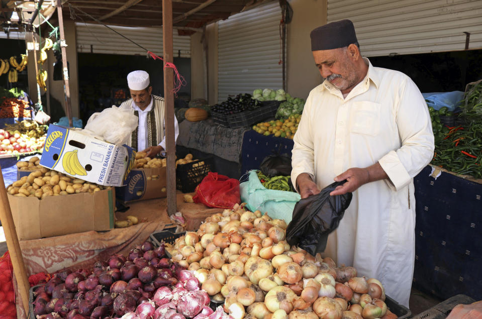 In this April 30, 2019 photo, men shop at a market in Benghazi, Libya. After years of assassinations, bombings and militia firefights, Libya’s eastern city of Benghazi finally feels safe again -- but security has come at a staggering cost. The city center lies in ruins, thousands of people remain displaced, and forces loyal to Khalifa Hifter, who now controls eastern Libya, have cracked down on dissent. But streets are cleaner, garbage is being collected and the electricity cuts out far less often than it did at the height of the fighting. (AP Photo/Rami Musa)