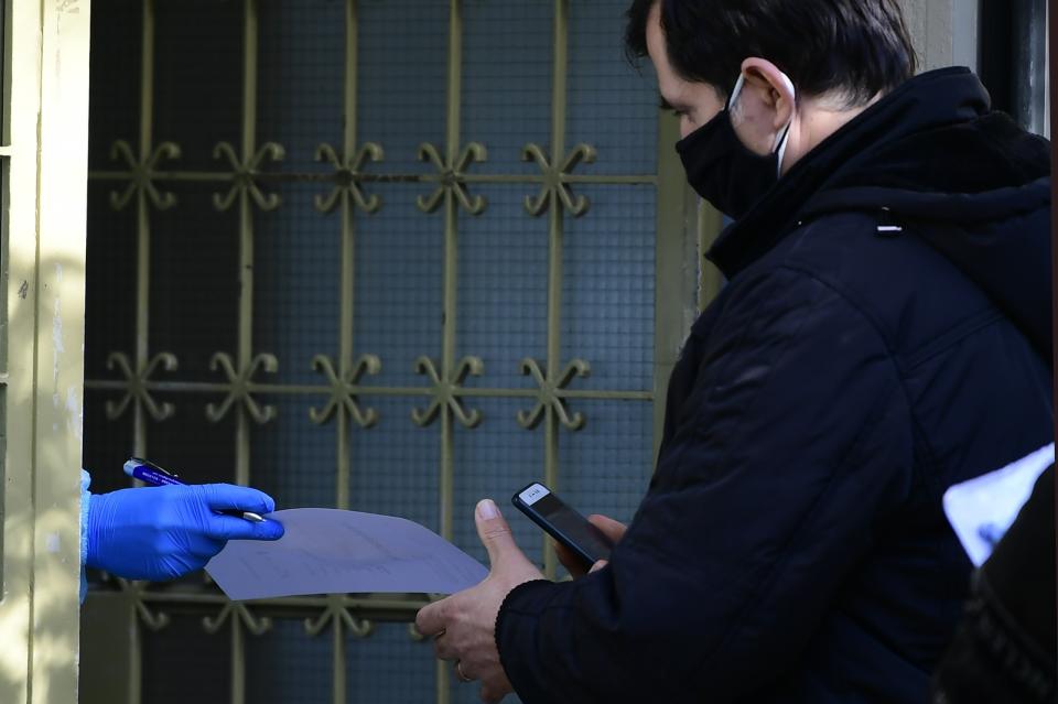 A medical staff checks the documents of a man before conducting a COVID-19 rapid test at Health Center in Athens, Greece, Tuesday, Jan. 4, 2022. A vaccination mandates for country residents over 60 goes into effect later this month as a surge in infections driven by the omicron variant of COVID-19 continues. Authorities will decide later today whether to reopen schools on schedule on Jan. 10. (AP Photo/Michael Varaklas)