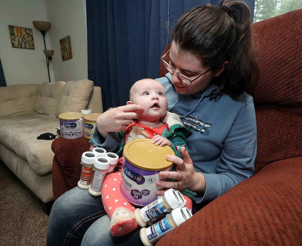 Sarah van Uitert's daughter Eliza looks up at her as she holds various containers of formula at their home in South Kitsap on Thursday. Uitert has relied on relatives in Oregon to scan shelves for formula when stores in Kitsap County were running low.