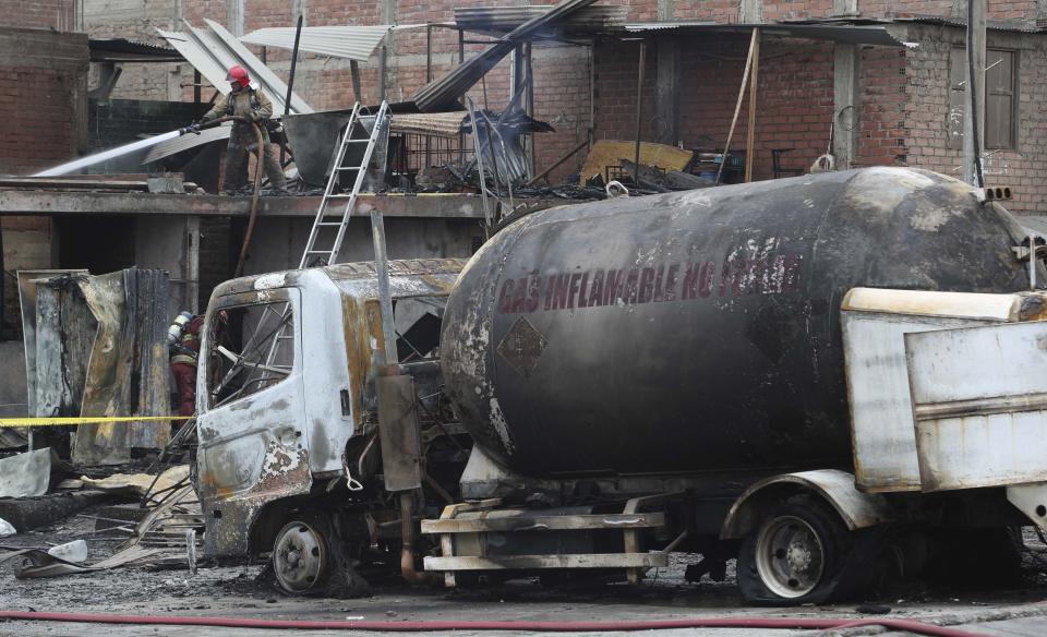 Un bombero enfría con agua el techo de un camión cisterna de gas que explotó en el barrio de Villa María en Lima, Perú, el jueves 23 de enero de 2020. La explosión dejó dos muertos, aproximadamente 50 personas heridas y al menos una docena de casas quemadas. (AP Foto / Martín Mejía)