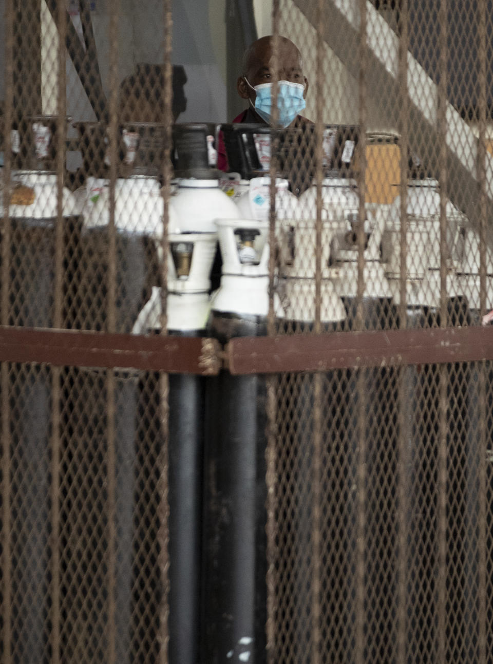 A health worker wearing a mask takes stock of oxygen cylinders inside a cage at a makeshift emergency unit at Steve Biko Academic Hospital in Pretoria, South Africa, Monday, Jan. 11, 2021, which is battling an ever-increasing number of Covid-19 patients. (AP Photo/Themba Hadebe)