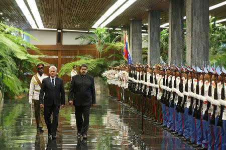 Cuban President Miguel Diaz-Canel (L) and Venezuela's President Nicolas Maduro review an honour guard during a ceremony at the Revolution Palace in Havana, Cuba April 21, 2018. REUTERS/Alexandre Meneghini