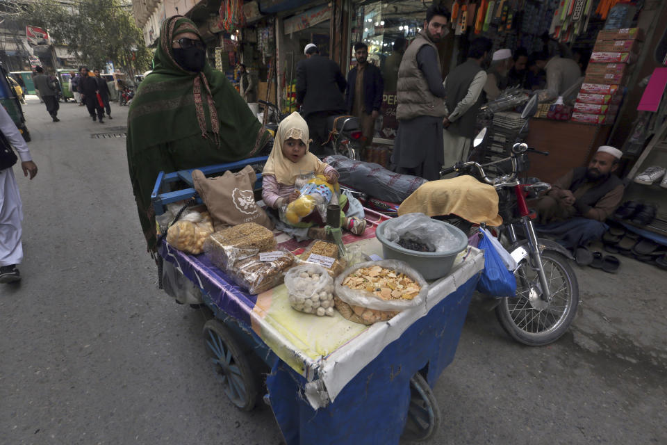 A woman sells snakes on a pushing cart at a market in Peshawar, Pakistan, Friday, Feb. 17, 2023. Many laborers are worried how they will survive after the government advanced a bill to raise 170 billion rupees in tax revenue. That could worsen impoverished Pakistan's economic outlook as it struggles to recover from devastating summer floods and a wave of violence. (AP Photo/Muhammad Sajjad)