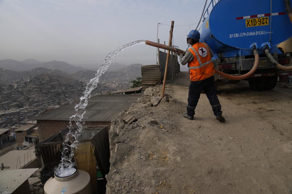 A water truck worker fills a container outside the homes of residents who use it for drinking, cooking and cleaning, in the Pamplona Alta area in Lima, Peru, Friday, March 8, 2024. Peru’s government gives potable water to 1.5 million of its poorest residents living in the hills. (AP Photo/Martin Mejia)