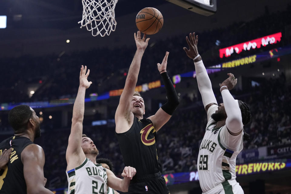 Cleveland Cavaliers guard Sam Merrill shoots between Milwaukee Bucks guard Pat Connaughton (24) and forward Jae Crowder (99) during the first half of an NBA basketball game, Wednesday, Jan. 17, 2024, in Cleveland. (AP Photo/Sue Ogrocki)