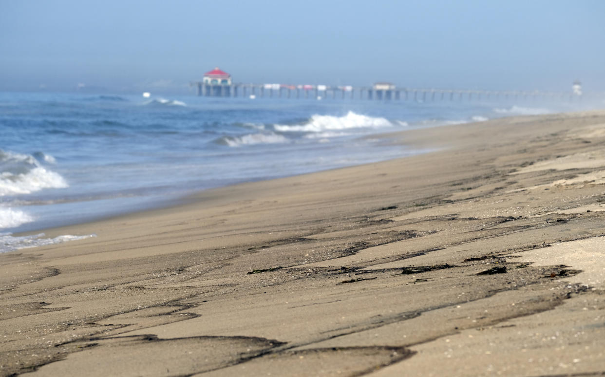 Patches of an oil spill wash off the beach south of the Pier in Huntington Beach, Calif., Sunday, Oct. 3, 2021. The closure stretched from the Huntington Beach Pier nearly 4 miles (6.4 kilometers) south to the Santa Ana River jetty amid summerlike weather that would have brought beachgoers to the wide strand for volleyball, swimming and surfing. Yellow caution tape was strung between lifeguard towers to keep people away. (AP Photo/Ringo H.W. Chiu)