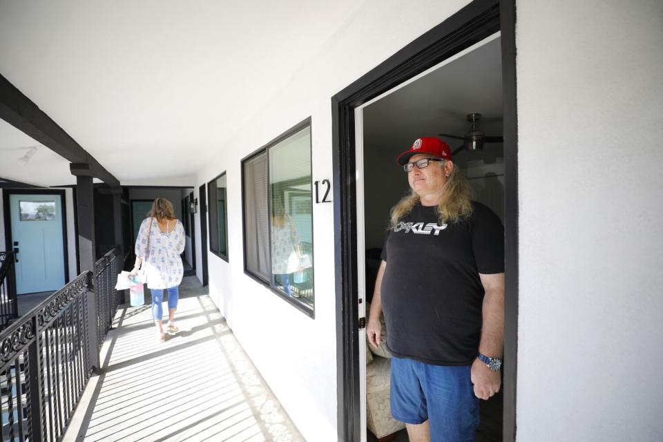 A man stands at the door of an apartment.