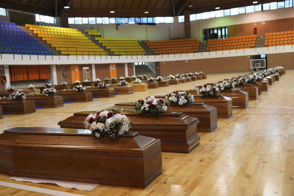 The coffins of the victims of last Sunday's shipwreck are lined up at the local sports hall in Crotone, southern Italy, Tuesday, Feb. 28, 2023. At least 65 people, including 14 minors, died when their overcrowded wooden boat slammed into shoals 100 meters (yards) off the shore of Cutro and broke apart early Sunday in rough seas. Eighty people survived, but many more are feared dead since survivors indicated the boat had carried about 170 people when it set off last week from Izmir, Turkey. (Antonino D'Urso/LaPresse via AP)