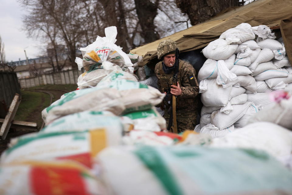 A Ukrainian soldier stands among sandbags at a checkpoint. 