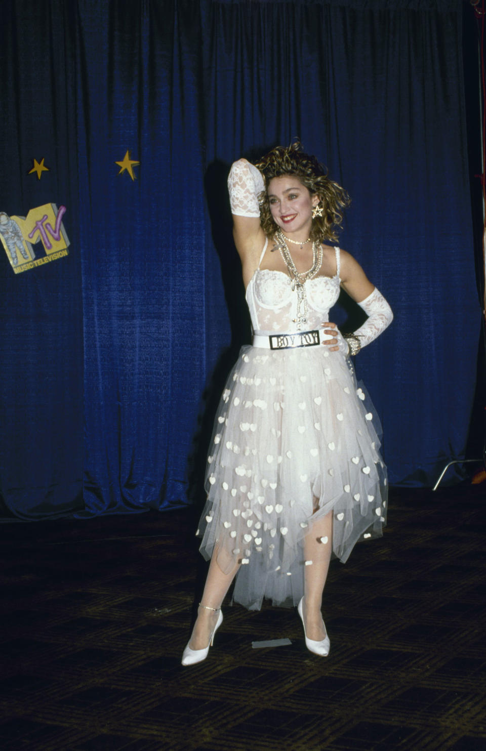 <p>Die „Queen of Pop“ setzte bei den allerersten MTV Video Music Awards gleich ein modisches Zeichen und hievte sich damit in den Fashion-Olymp der legendärsten VMA-Outfits. Passend zu ihrem Song „Like a Virgin“ erschien Madonna 1984 in einem Bustier-Dress, das einem Hochzeitskleid ähnelte. Passend dazu trug sie weiße Spitzenhandschuhe und Pumps. Das Highlight aber war der auffällige Gürtel mit den Worten „Boy Toy“ (deutsch: junger Liebhaber, ähnlich wie „Toy Boy“). (Bild: Getty Images) </p>