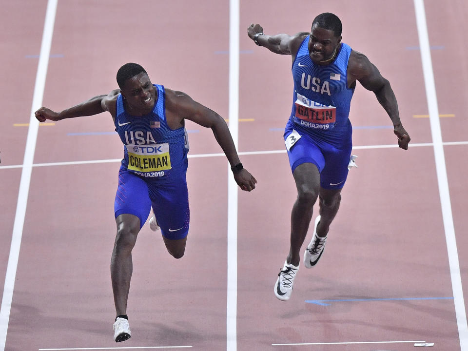 Christian Coleman, of the United States, left, crosses the finish line to win the men's 100 meter race ahead of silver medalist Justin Gatlin, of the United States, right, during the World Athletics Championships in Doha, Qatar, Saturday, Sept. 28, 2019. (AP Photo/Martin Meissner)