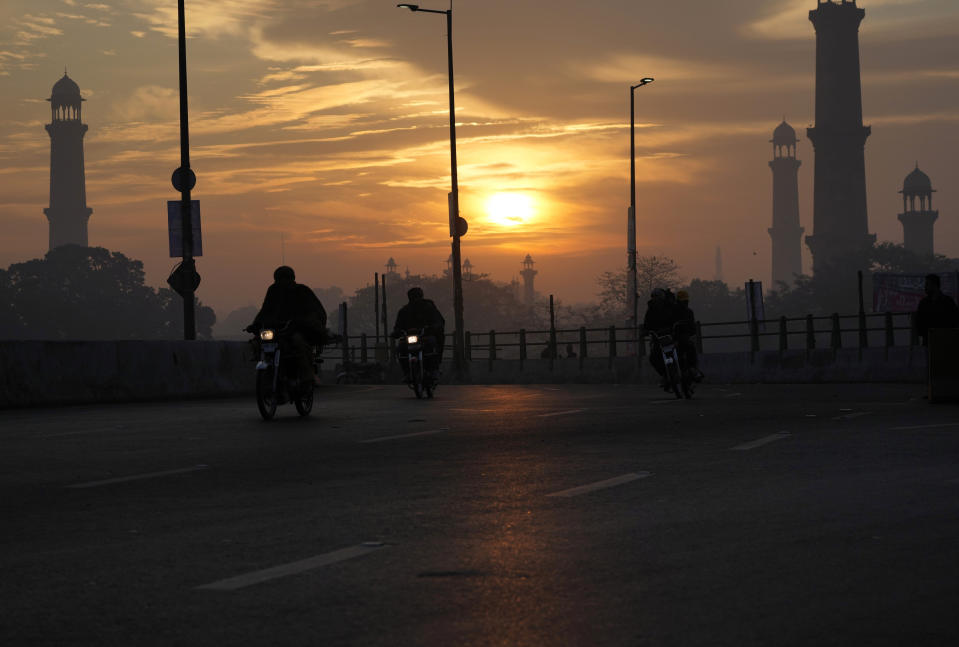 People ride a motorbike at sunrise on New Year's Day in the city of Lahore, Pakistan, Sunday, Jan. 1, 2023. (AP Photo/K.M. Chaudary)