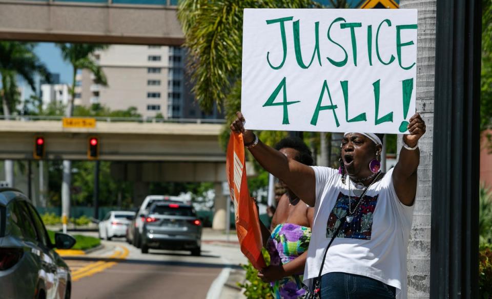 Fort Myers resident Tracy Howards holds a signs while protesting in downtown Fort Myers Friday afternoon, March 15, 2024. Members of the Lee County NAACP held a rally in front of the office of the state attorney to protest the handling of the Fort Myers Police Department fatal shooting of Christopher Jordan on December 1, 2023.