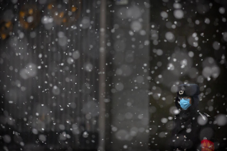 A security guard wears a face mask as he stands during a snowfall in Beijing, Friday, Feb. 14, 2020. China on Friday reported another sharp rise in the number of people infected with a new virus, as the death toll neared 1,400. (AP Photo/Mark Schiefelbein)