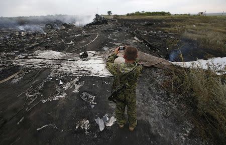 An armed pro-Russian separatist takes pictures at the site of a Malaysia Airlines Boeing 777 plane crash near the settlement of Grabovo in the Donetsk region, July 17, 2014. REUTERS/Maxim Zmeyev