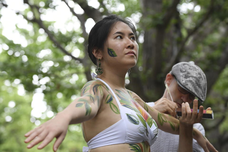Miho Nakashima has her body painted like a tree by artist Andy Boerger during a public protest on Sunday, Aug. 27, 2023, to point out that 100-year-old trees in the Jingu Gaien park area in Tokyo, Japan, could be cut down under a disputed development plan.(AP Photo/Norihiro Haruta)