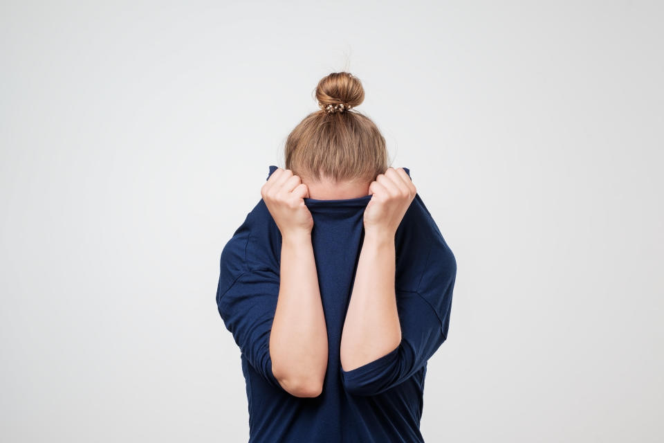 Woman hiding face under her jumper. Wanting to be left alone.