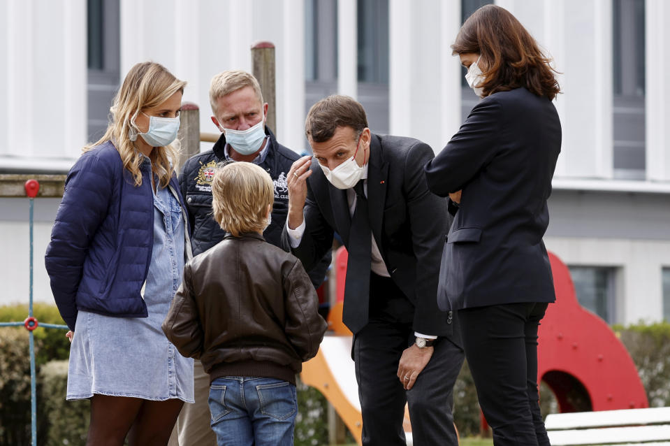 French President Emmanuel Macron talks to a child as he visits a child psychiatry department at Reims hospital, eastern France, to discuss the psychological impact of the COVID-19 crisis and the lockdown on children and teenagers in France, Wednesday, April 14, 2021. (Christian Hartmann/Pool via AP)