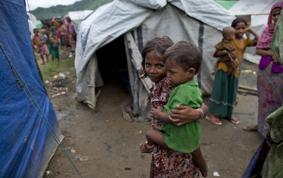 In this Sep 17, 2013 photo, Muslim girl who become displaced following 2012 sectarian violence carries a baby at Nga Chaung Refugee Camp in Pauktaw, Rakhine state, Myanmar. Severe shortages of food, water and medical care for Rohingya Muslims in western Myanmar are part of a long history of persecution against the religious minority that could amount to "crimes against humanity," according to a statement released Monday April 7, 2014, from Tomas Ojea Quintana, the U.N. Special Rapporteur on the human rights situation in the country. (AP Photo/Gemunu Amarasinghe)