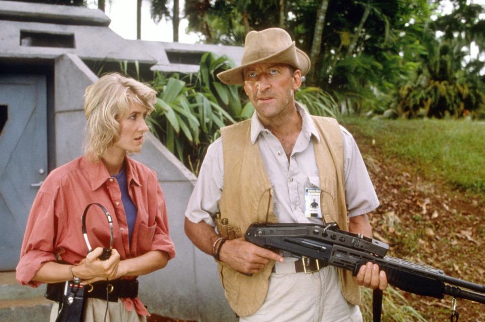 Laura Dern and Bob Peck in outdoor adventure gear with a futuristic building in the background, from a scene in Jurassic Park