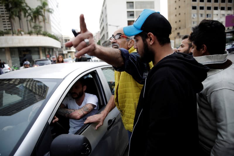 A protester gives directions to fellow protesters to open a roadblock for a driver during ongoing anti-government demonstrations in Beirut