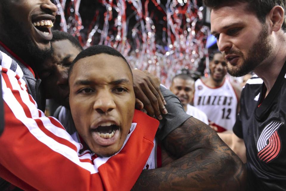 Portland Trail Blazers' Damian Lillard, center, celebrates his winning shot against the Houston Rockets during the last .9 of a second of game six of an NBA basketball first-round playoff series game in Portland, Ore., Friday May 2, 2014. The Trail Blazers won the series in a 99-98 win. (AP Photo/Greg Wahl-Stephens)