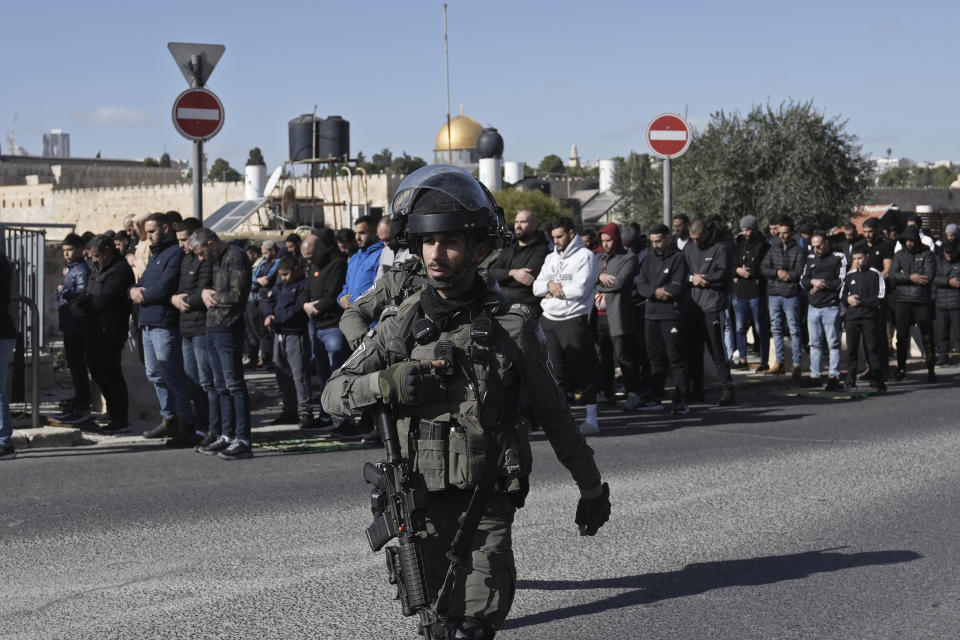 Palestinian Muslim worshipers who were prevented from entering the Al-Aqsa Mosque pray outside Jerusalem's Old City as Israeli forces stand guard Friday Dec. 22, 2023. (AP Photo/Mahmoud Illean)