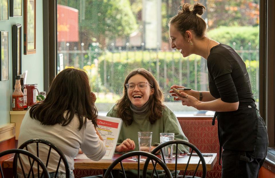 Clark University seniors Ellen Choe, left, and Lucy Fleming share a laugh with waitress Bea Gerber while ordering breakfast Friday at Annie’s Clark Brunch.