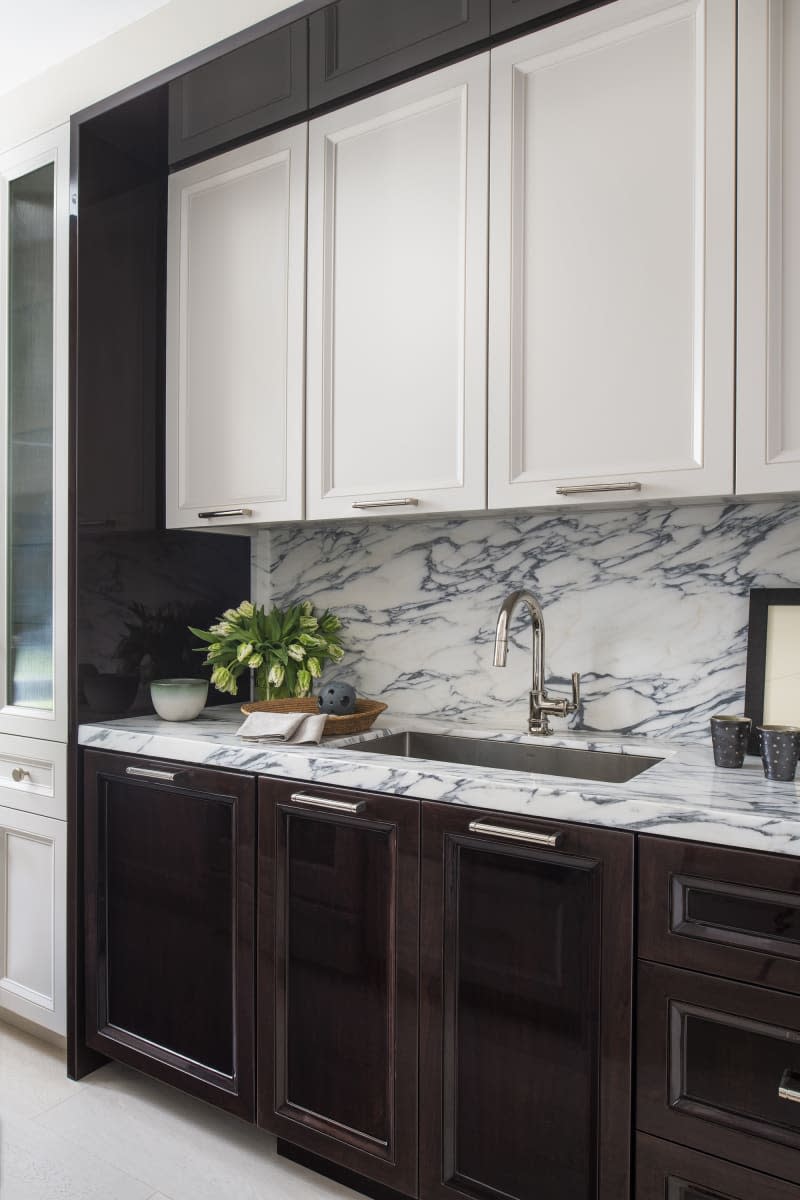 kitchen with marble counter and backsplash with white and dark brown cabinets