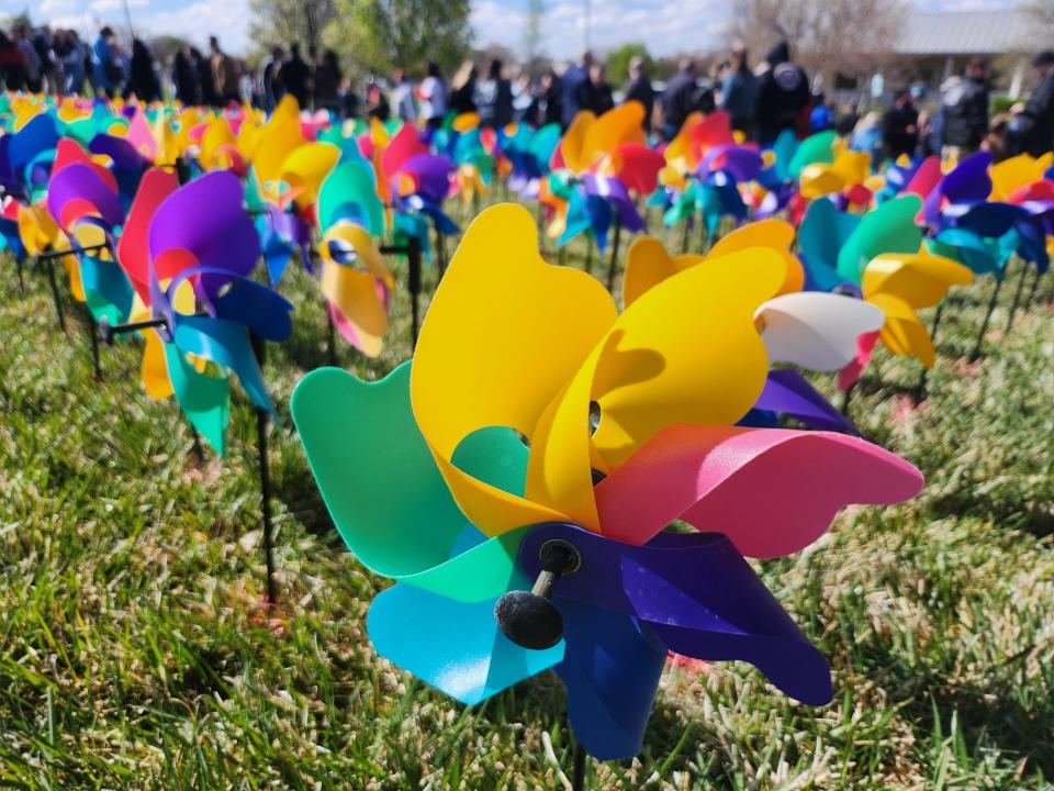 Crowds of individuals representing area law enforcement, first responders, child care advocates, and more plant over 1,000 pinwheels on the front lawn of The Bridge Children's Advocacy Center to spread awareness for Child Abuse Prevention Month.