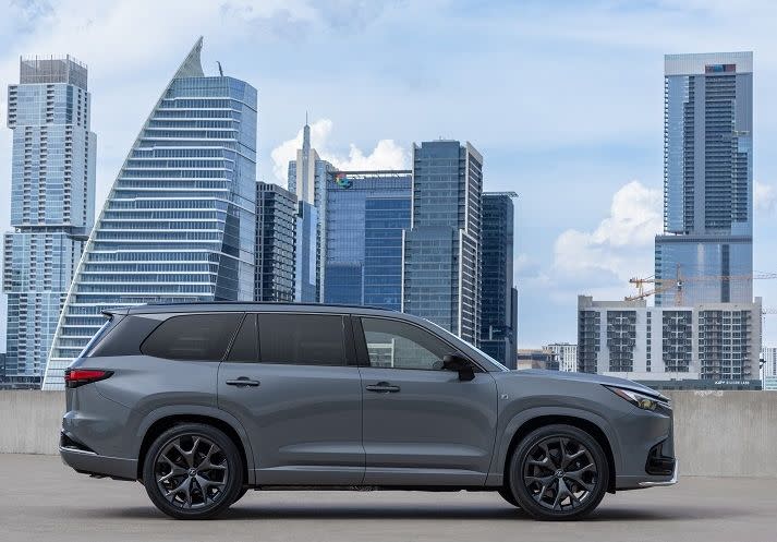 a silver car on a road with a city skyline in the background